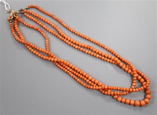 An early-mid 20th century triple strand graduated coral bead necklace, with yellow metal and coral bead set clasp, 51cm.